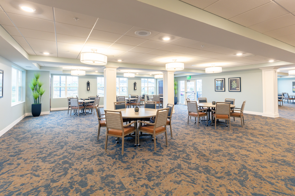 Spacious and bright dining area with round tables, modern lighting, and large windows.