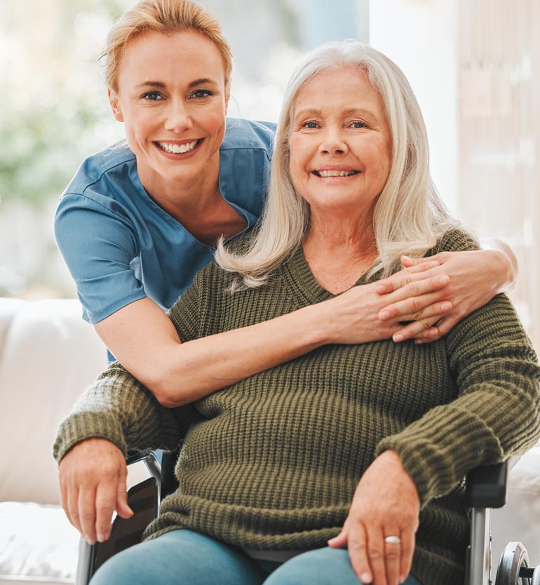 senior-healthcare Smiling healthcare worker embracing and supporting a happy senior woman in a wheelchair.