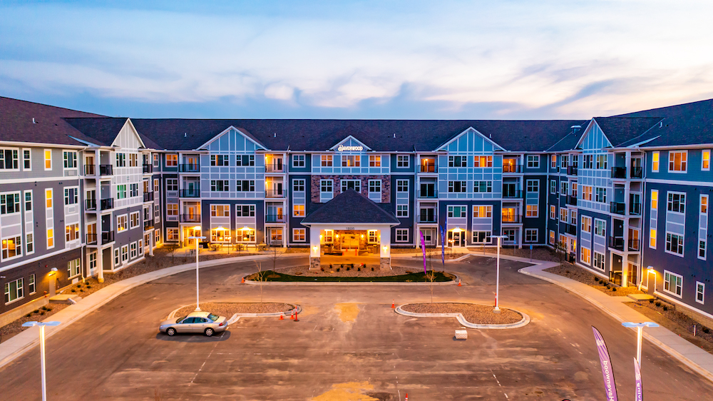 A large four-story building with a central entrance and illuminated windows at dusk.