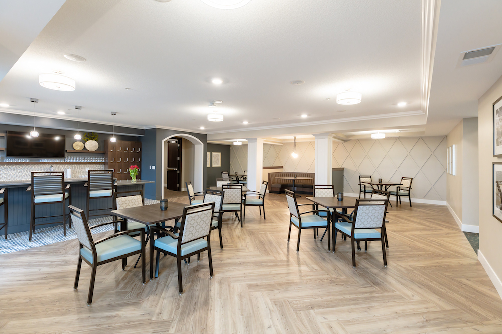Modern dining area with wooden flooring, tables, chairs, a bar counter, and soft lighting.