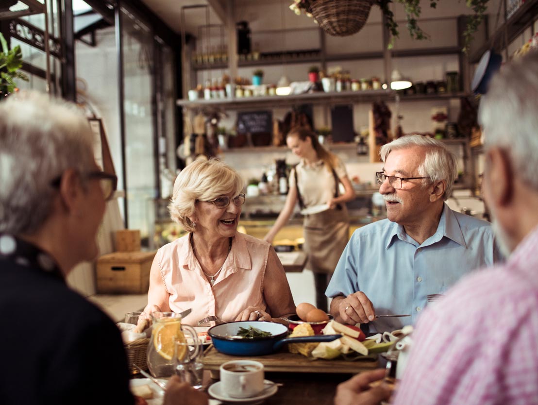 senior-dining Group of senior friends joyfully dining together at a cozy restaurant during the daytime.