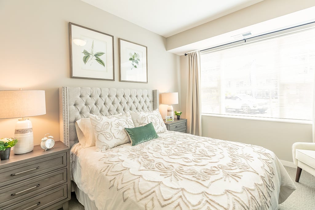 Bright bedroom with large window and green decoration accents.