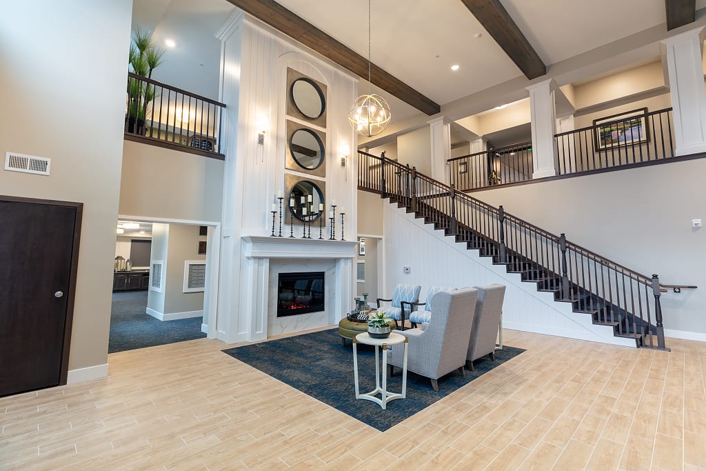 Spacious lobby with two story ceilings, a fireplace, and armchairs.