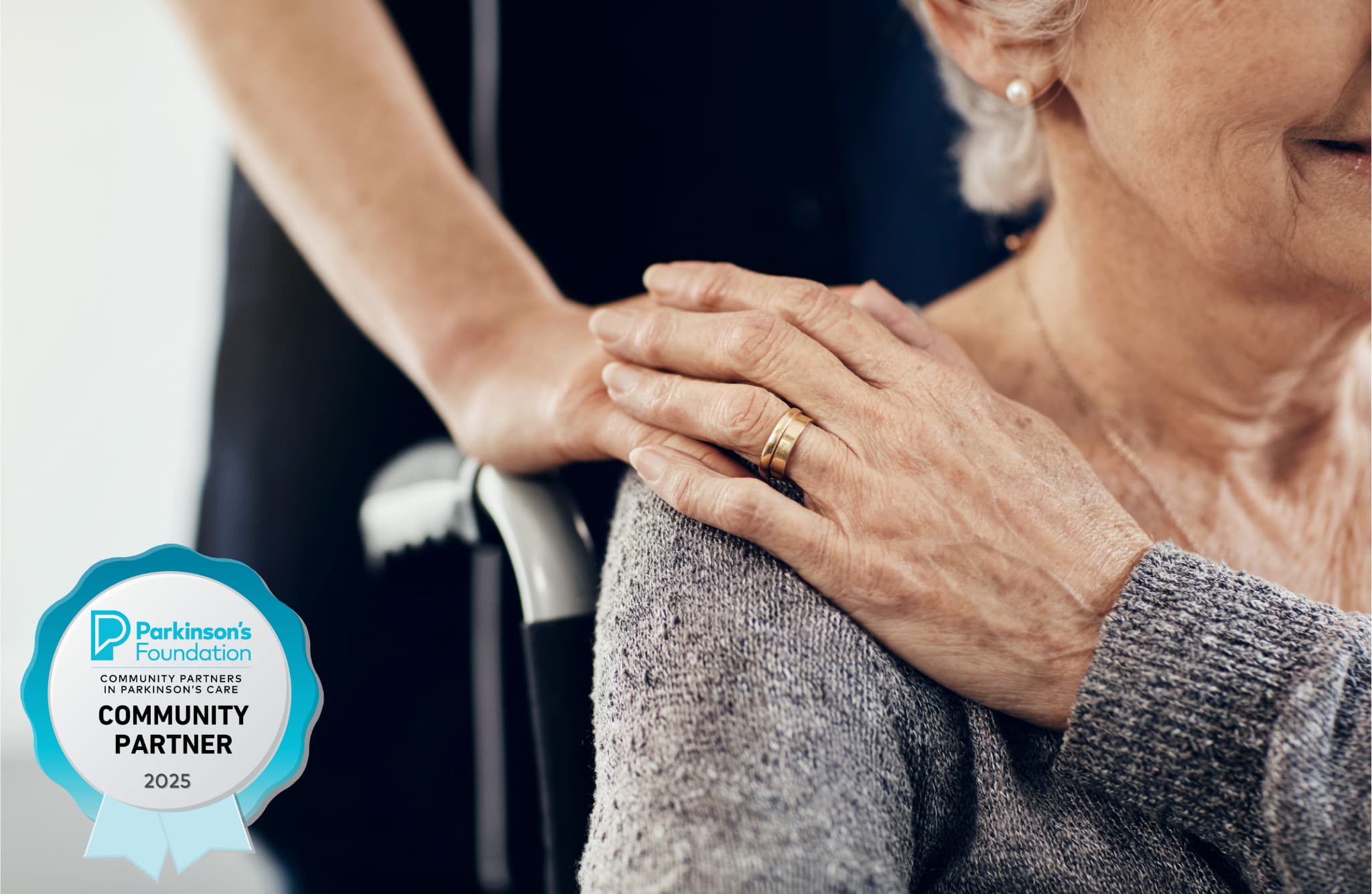 Senior woman in wheel chair holds hand with care giver